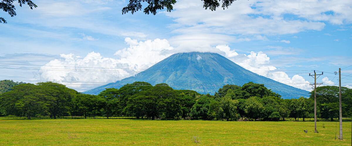 A grassy field with a mountain in the background.