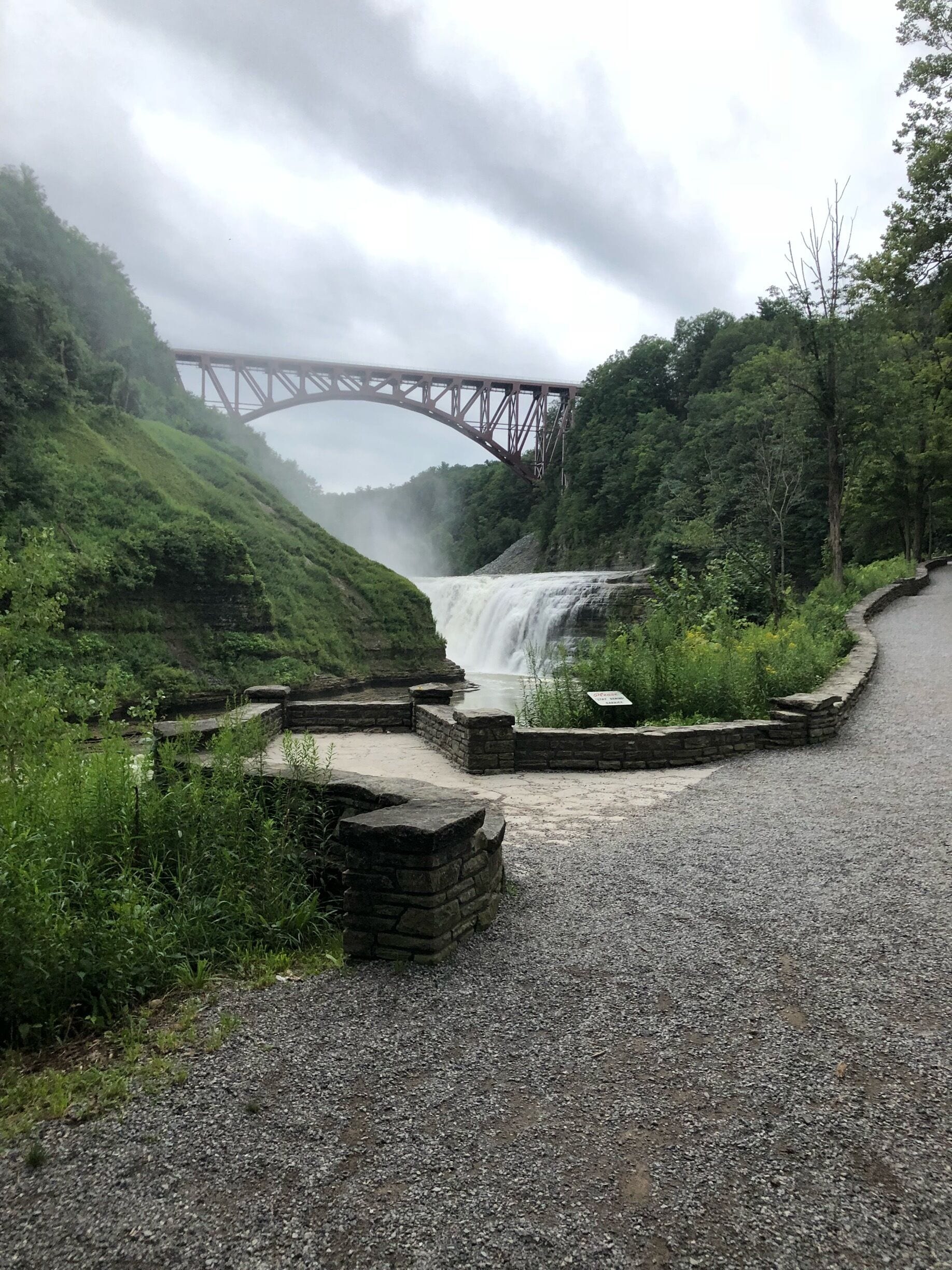A waterfall, a stone bridge, and lush greenery.