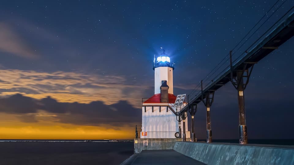 A lighthouse at dusk with a clear sky and a sunset.