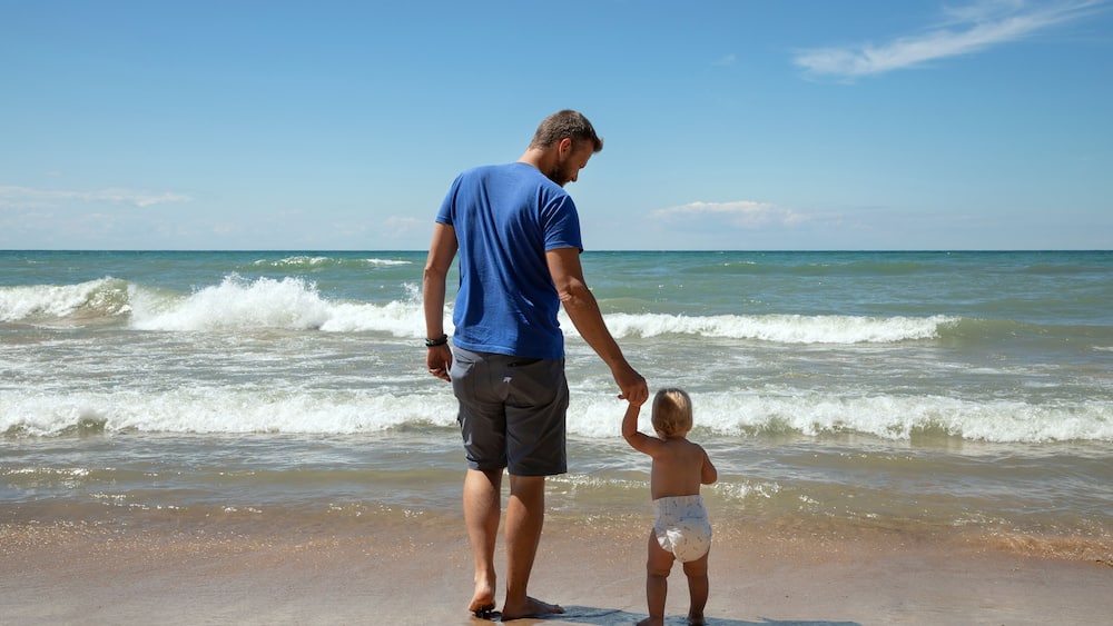 Father and 1 year old daughter at Indiana Dunes National Park in the summer gazing at Lake Michigan's waves