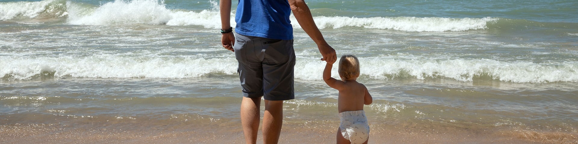 Father and 1 year old daughter at Indiana Dunes National Park in the summer gazing at Lake Michigan's waves