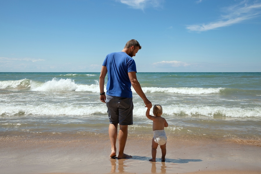 Father and 1 year old daughter at Indiana Dunes National Park in the summer gazing at Lake Michigan's waves