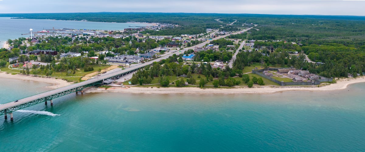 An aerial view of a coastal town with a bridge connecting to a peninsula, surrounded by water and greenery.
