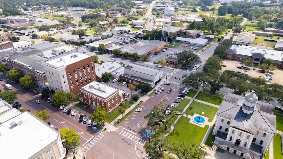 An aerial view of a town with a prominent water tower, a large white building with a dome, and a historic courthouse.