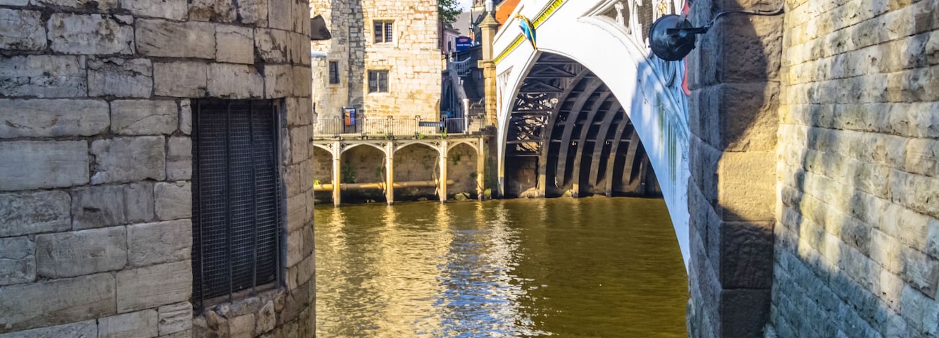A stone bridge over a canal with a chain barrier in the foreground.