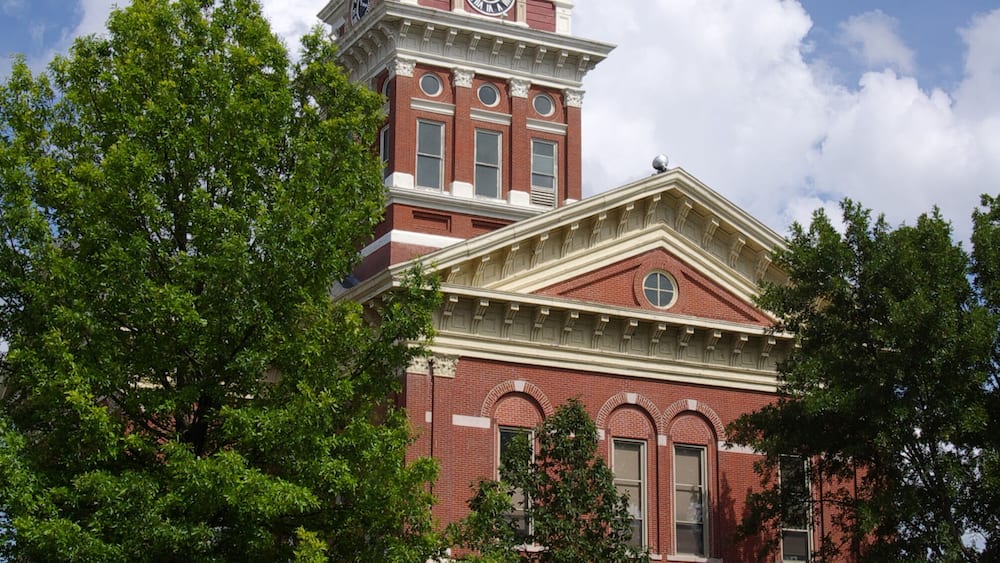 A large red brick building with a clock tower and a dome.