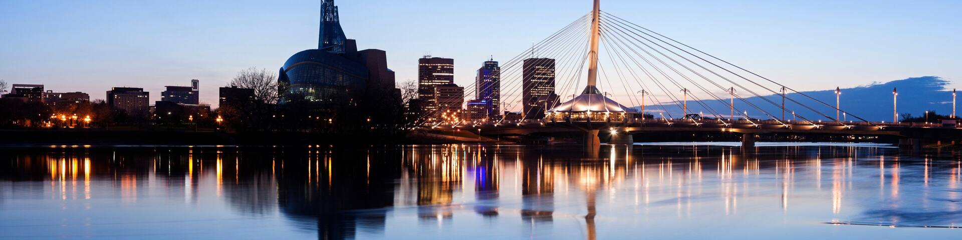 Illuminated skyline reflecting in calm Assiniboine River