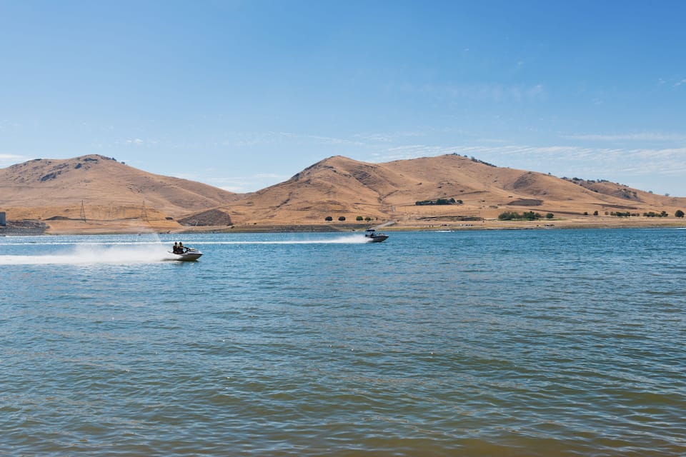 Um barco em um lago calmo, com montanhas ao fundo.