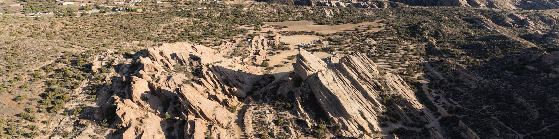 Un paysage montagneux accidenté, avec une végétation clairsemée et un chemin de terre sinueux.