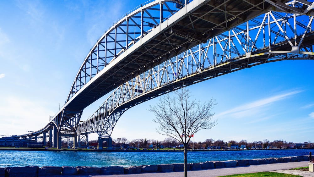 Eine große Stahlbrücke über einem Fluss, bewölkter, klarer Himmel.