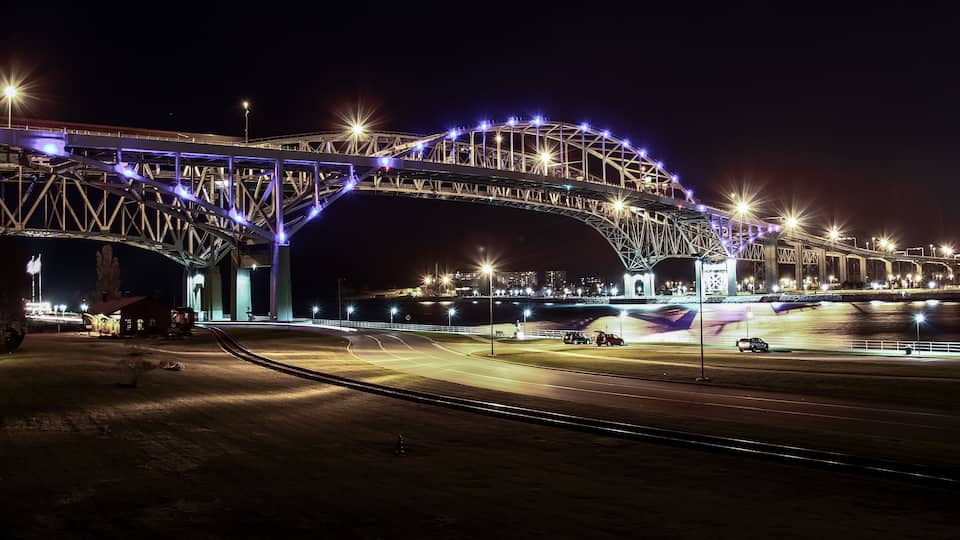 A brightly lit bridge at night with a river below.