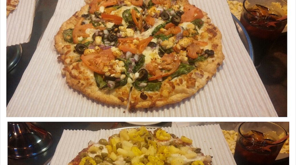 Up top, a Greek pizza with garlic olive oil, provolone, feta, spinach, black olives, tomato slices and red onions. Down below, a create your own with pineapple, red onions, green olives and banana peppers.