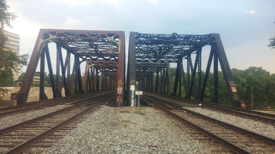 A railway bridge with multiple tracks and a signpost in the center.