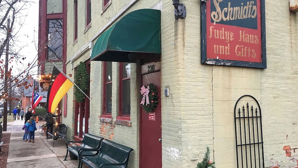 A building with a sign reading "Schmidts Fudge Haus und Gifts" and a Christmas tree decorated with candy canes.