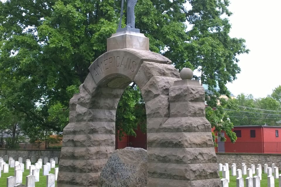 Ein Denkmal für Konföderierte Soldaten mit einer Statue auf der Spitze, umgeben von weißen Grabsteinen.