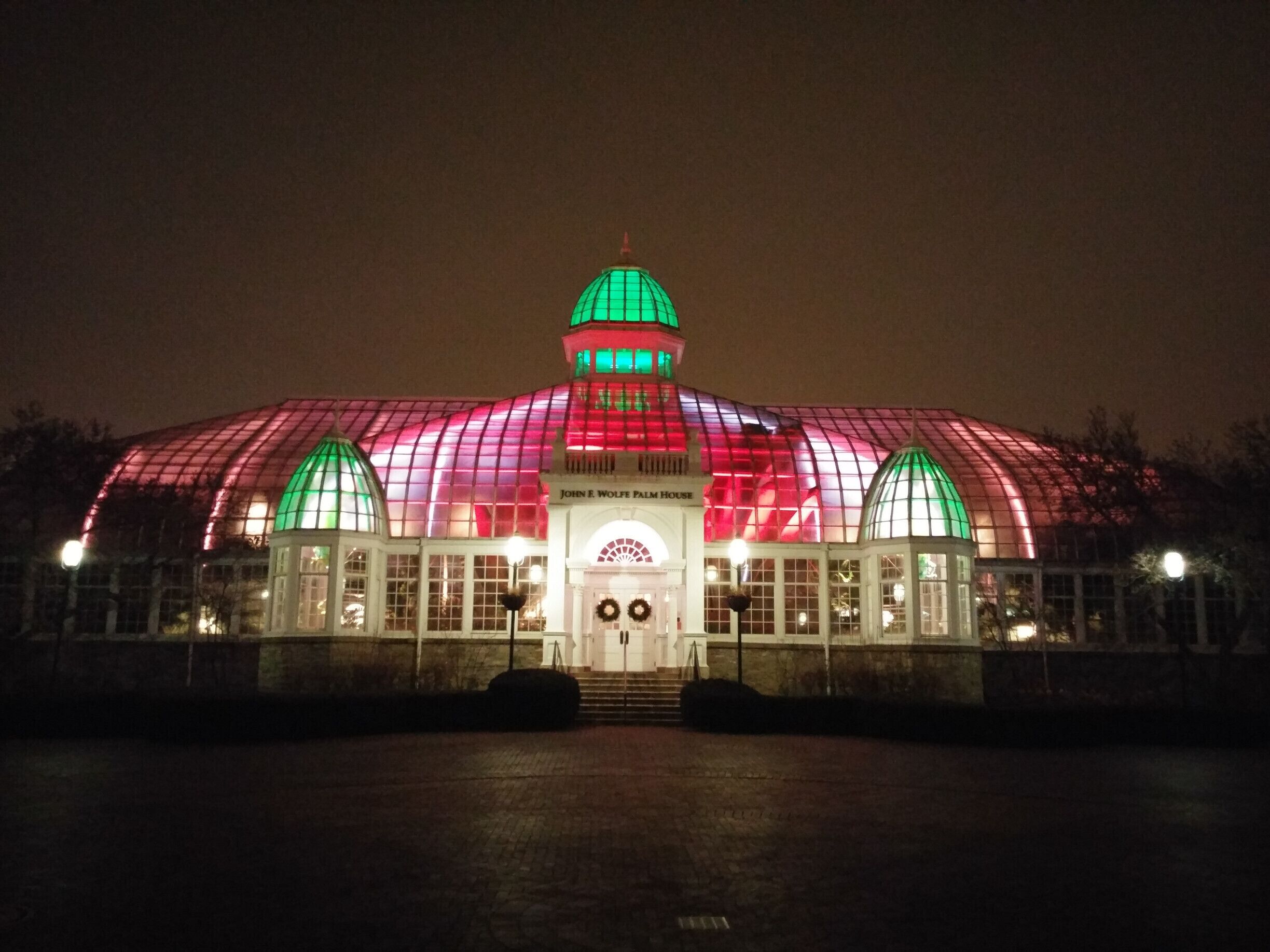 The John F. Wolfe Palm House lit up in holiday red and green. The palm house opened to the public in 1895. The light display was installed in 2008 by artist James Turrell, consisting of approximately 7,000 small, computer-controlled LED light sources.