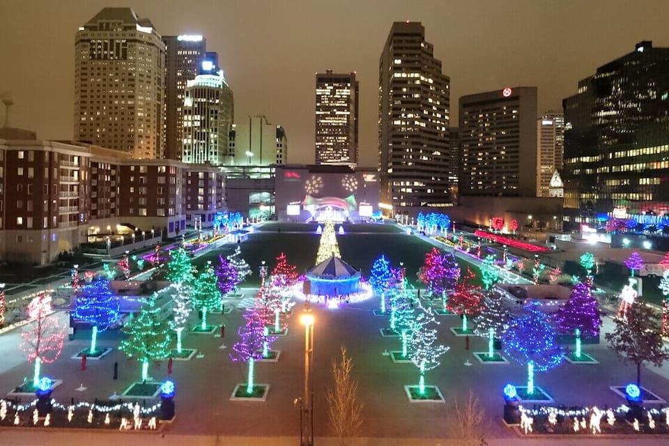 Paisagem urbana noturna com árvores e edifícios iluminados.