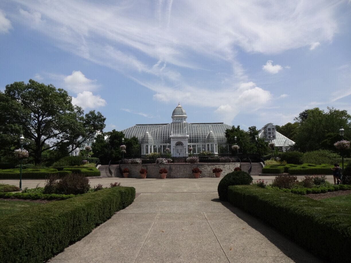 The John F. Wolfe Palm House at the Franklin Park Conservatory basking beneath blue skies and jet trails The palm house opened to the public in 1895.