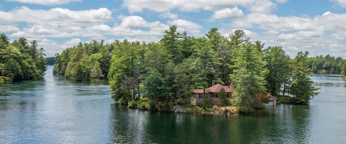 A house surrounded by dense forest on a lake.