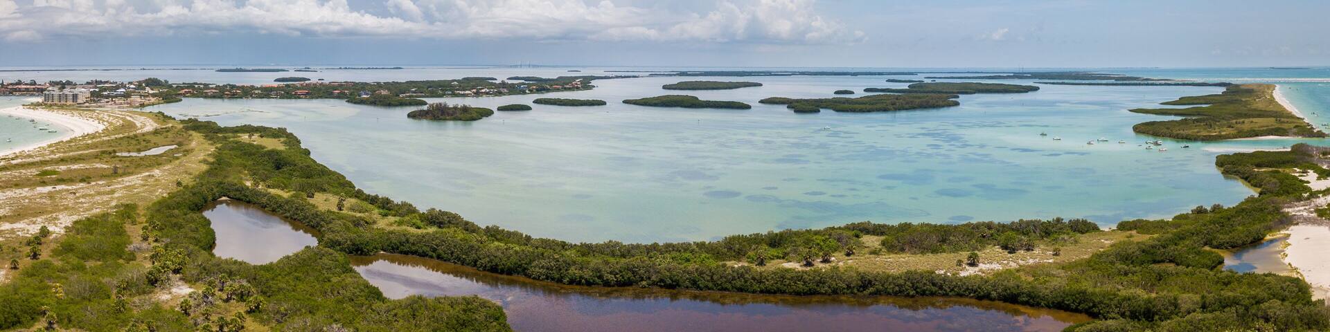 Un paysage côtier avec une baie, de nombreuses petites îles et un pont à l’horizon.