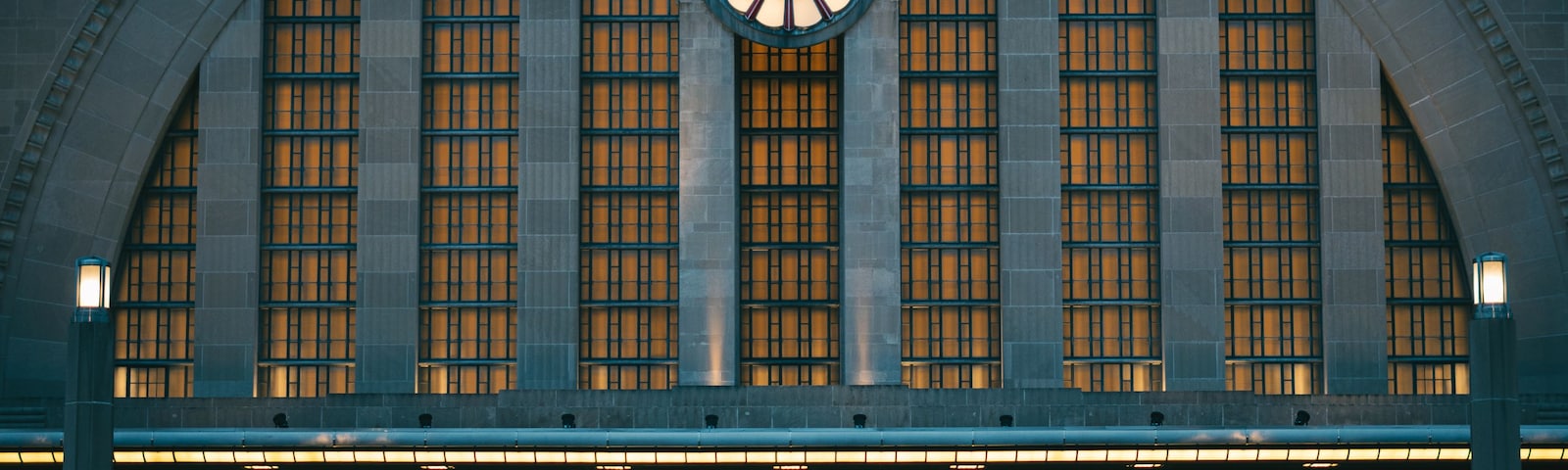 Un edificio imponente con un gran reloj en la fachada, ventanas arqueadas y una escalera que conduce a la entrada.