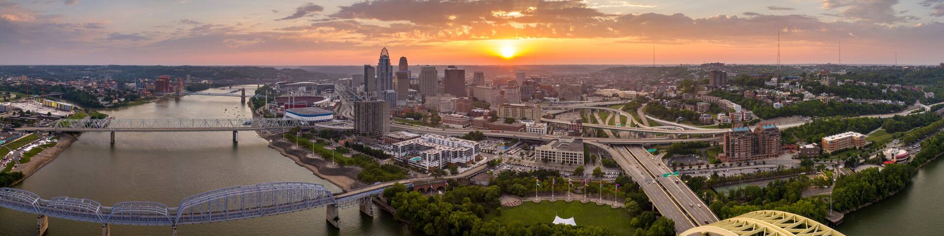 Driving cars on bridge highway near illuminated high skyscraper buildings in downtown district of Cincinnati, Ohio, USA. American city with business financial district at sunset