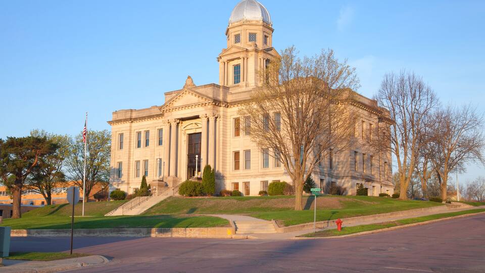 A large, historic building with a dome and columns, surrounded by trees and a clear sky.