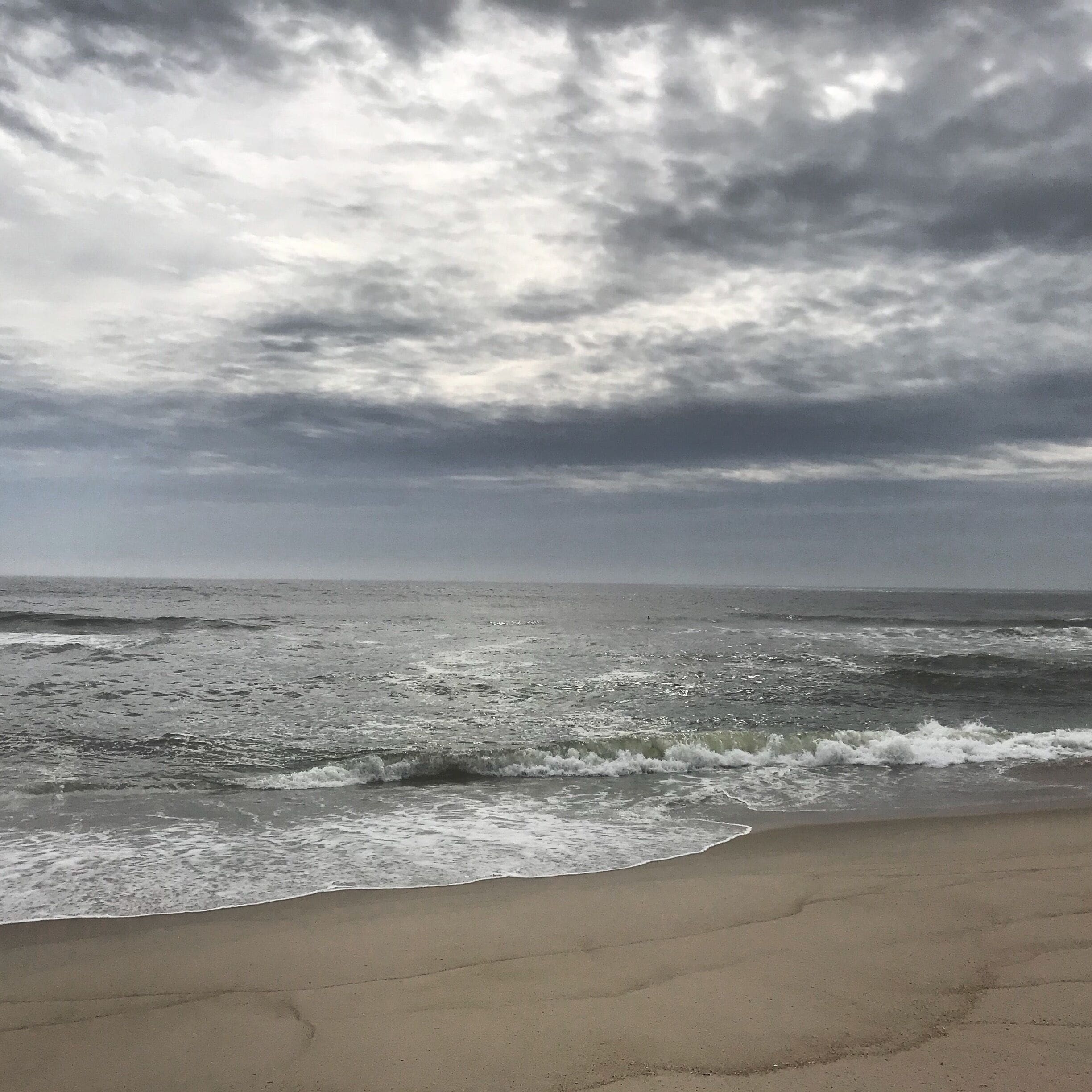 Una playa con olas y un cielo nublado.