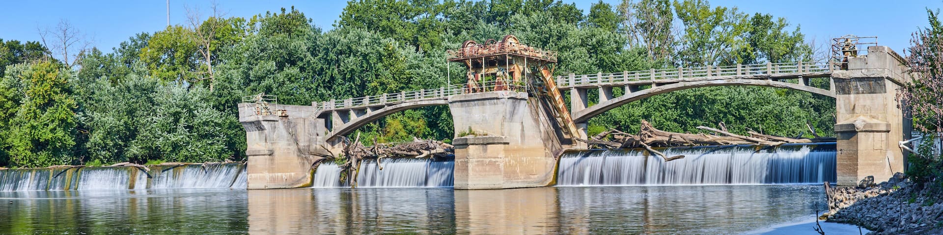 Maumee River Dam Fort Wayne, IN panorama on bright and sunny summer day with logs over waterfalls