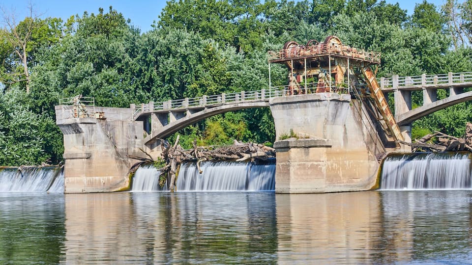 A stone bridge with a waterfall and lush greenery in the background.