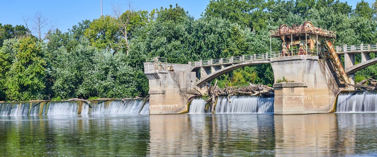 A stone bridge with a waterfall and lush greenery in the background.