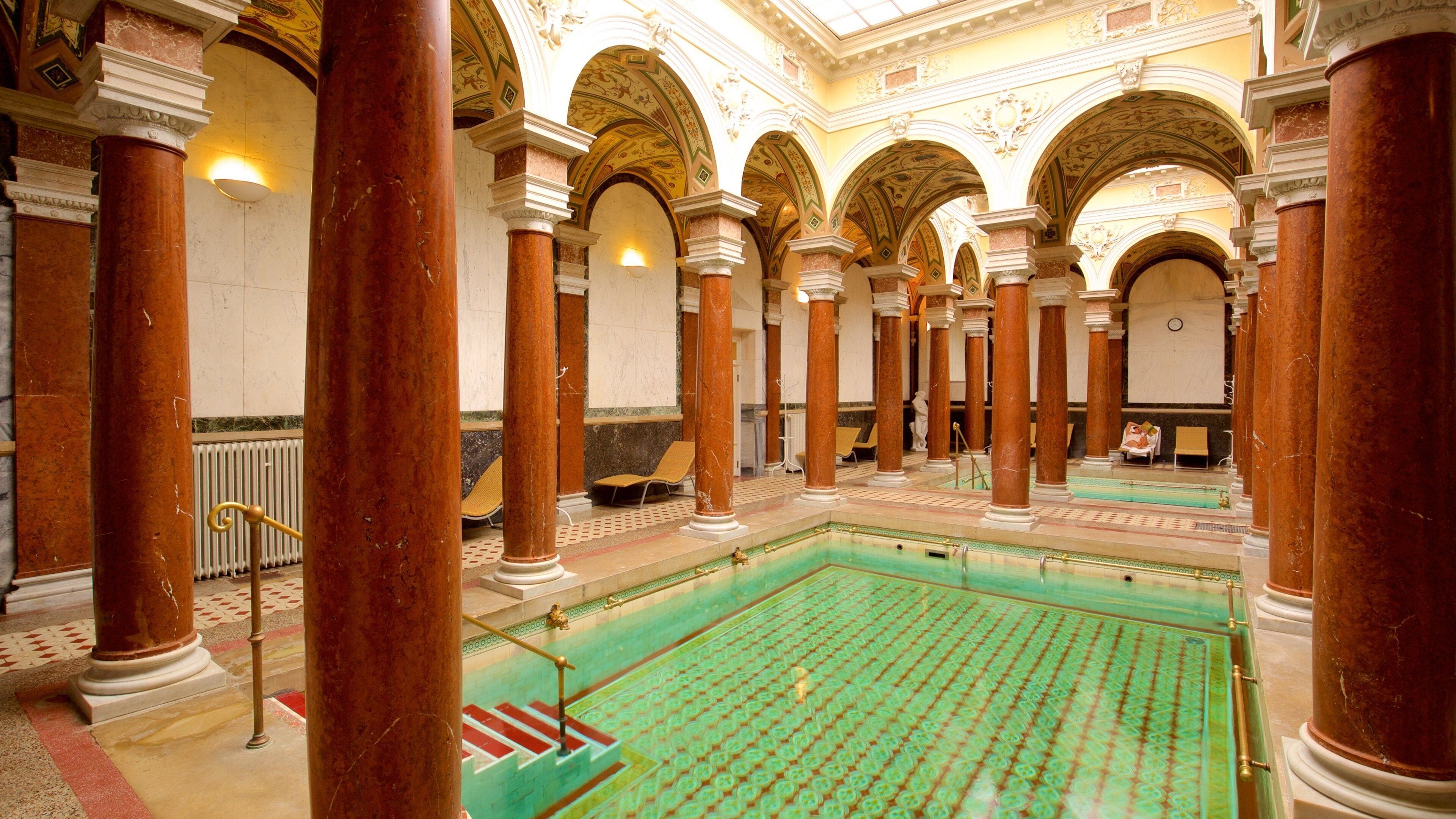 Una amplia piscina interior con columnas y arcos.