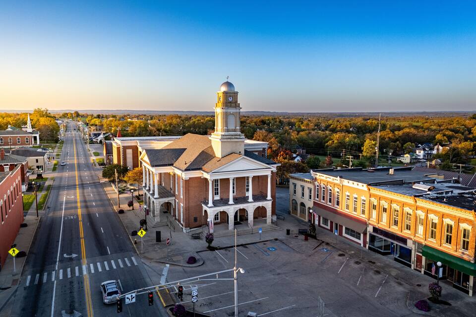 A town square with a prominent clock tower, intersecting roads, and surrounding buildings.