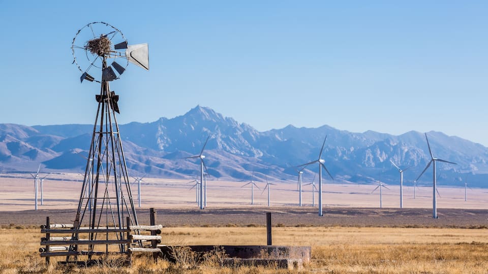A windmill in a field with mountains in the background.