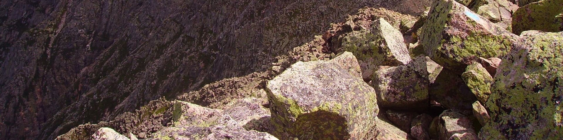 A rugged mountain peak with a lake in the distance.