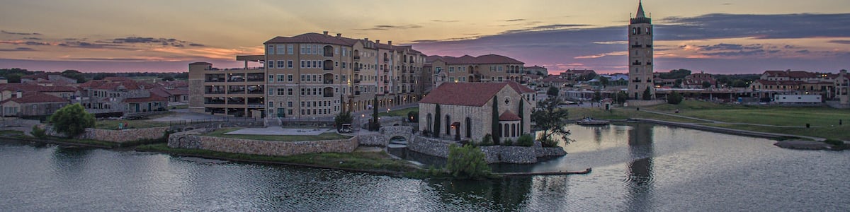 A riverside town with historic buildings, a church, and a prominent tower.