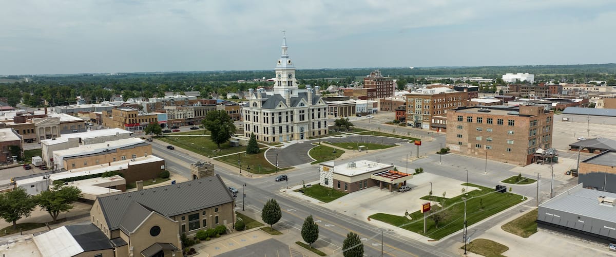 A cityscape with a prominent white building with a clock tower, surrounded by various other buildings and a clear sky.