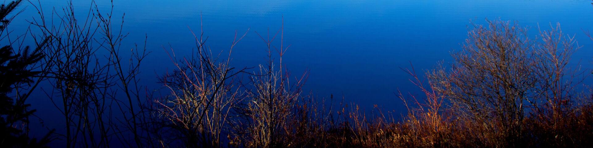 A calm lake surrounded by trees and hills.