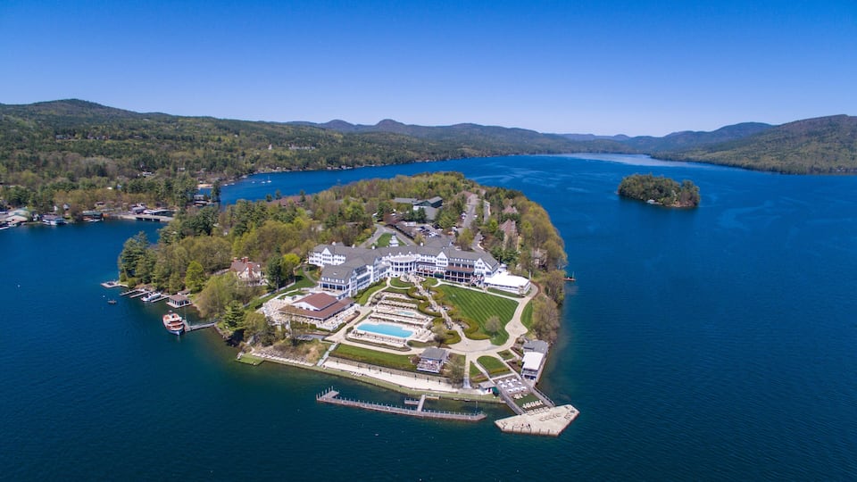 An aerial view of a lakeside resort with a large house, a swimming pool, and a dock.