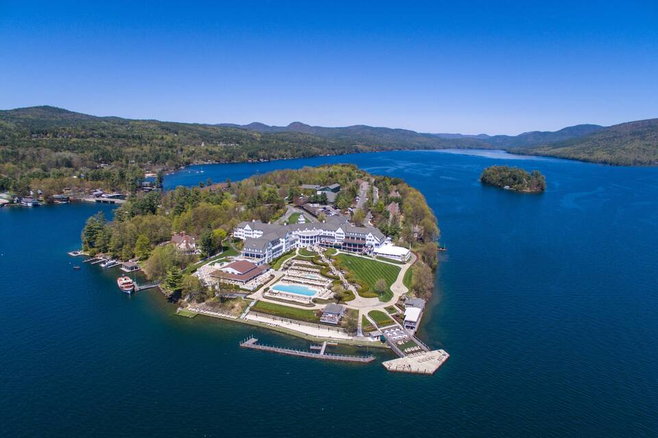 An aerial view of a lakeside resort with a large house, a swimming pool, and a dock.