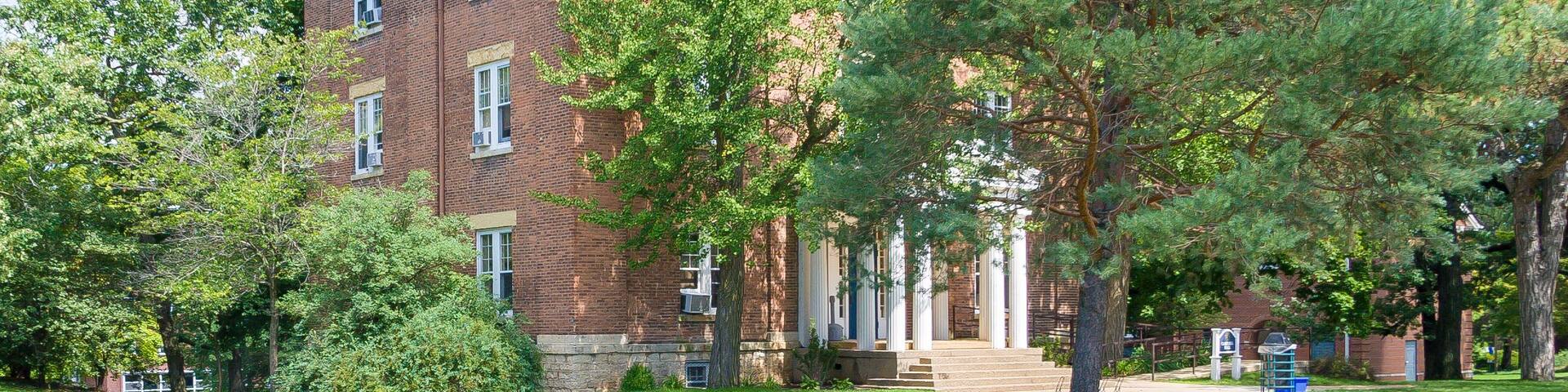 A brick building with a green lawn and a pathway leading to it.