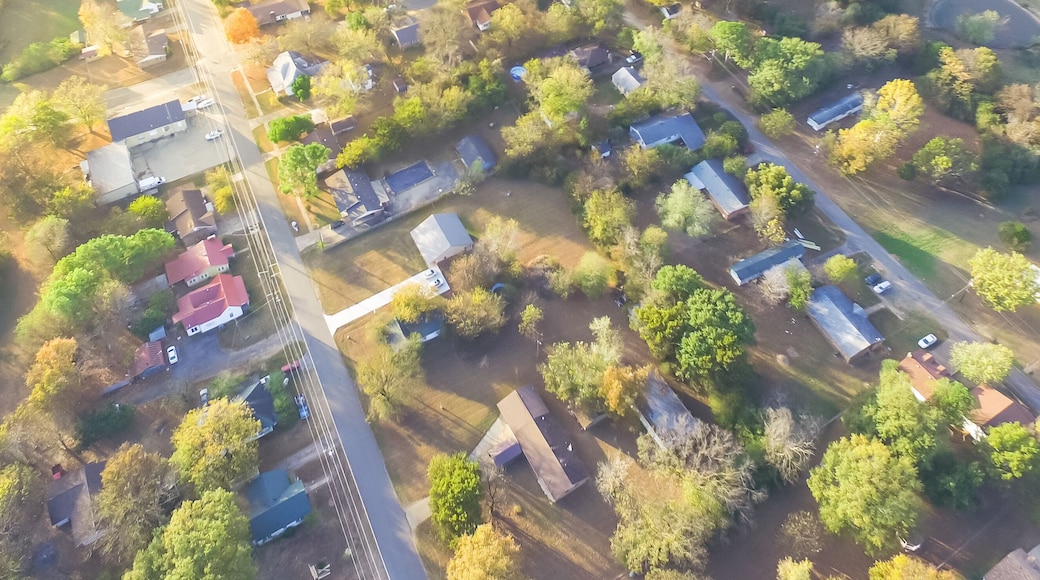 Panorama scenic aerial green suburban area of Ozark, Arkansas, USA. Overhead residential neighborhood tightly packed homes, driveway surround lush tree flyover in autumn sunset. View from East side