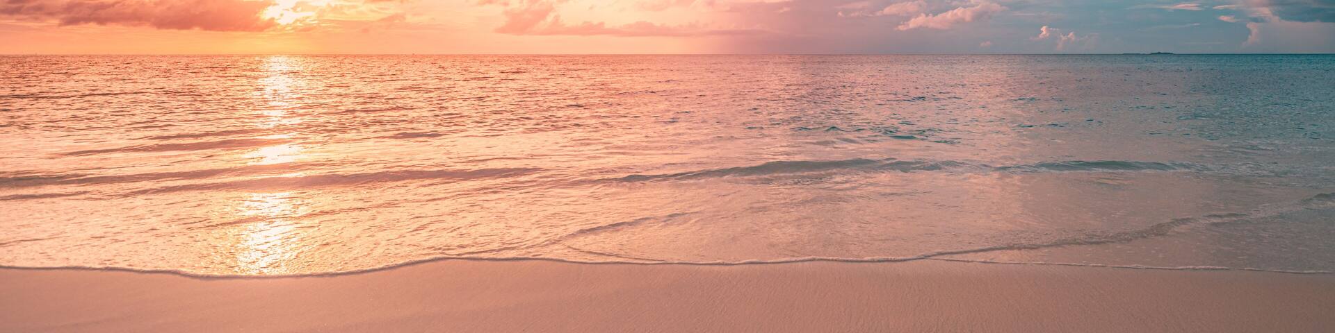 Une plage au coucher du soleil, avec des vagues et des nuages.
