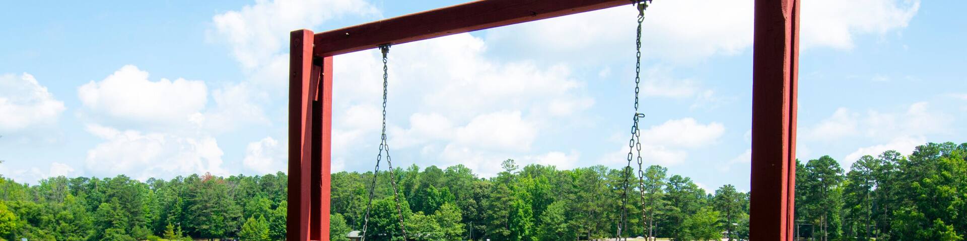 A wooden swing set by a lake with a clear sky.