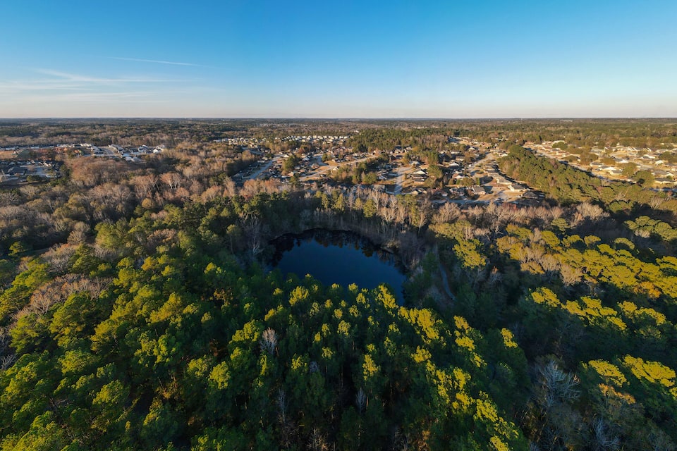 Vista aérea de un pueblo rodeado de bosques densos y un lago.