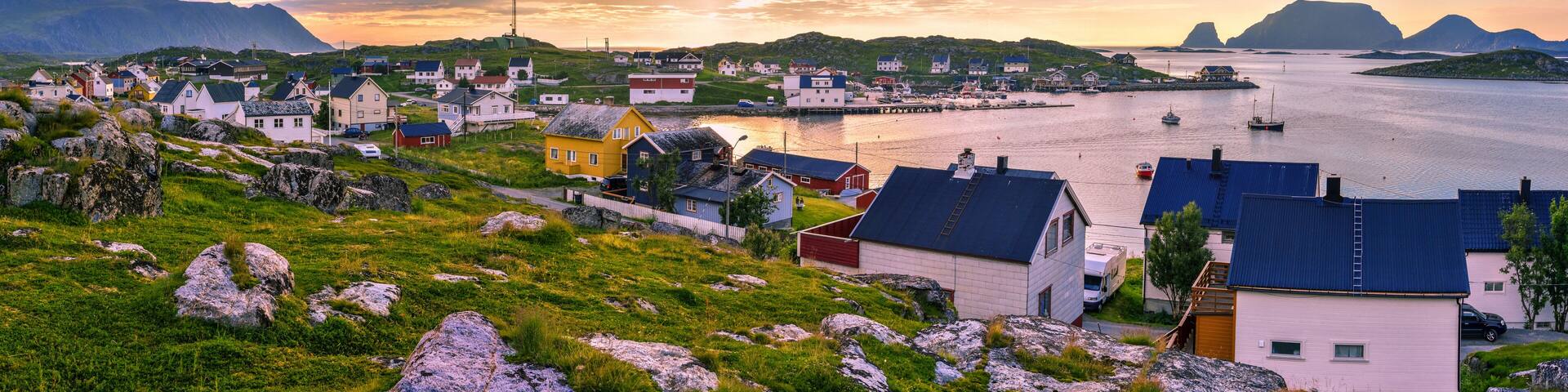 A coastal village with colorful houses, a dock, and a mountainous backdrop.