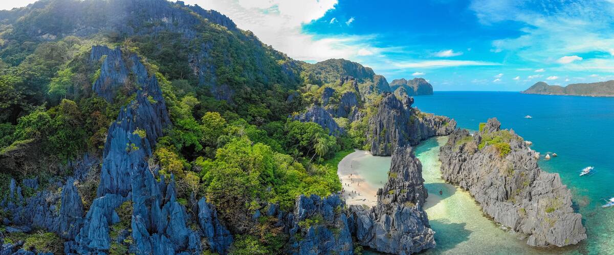 A coastal landscape with rugged cliffs, clear turquoise waters, and a small beach.