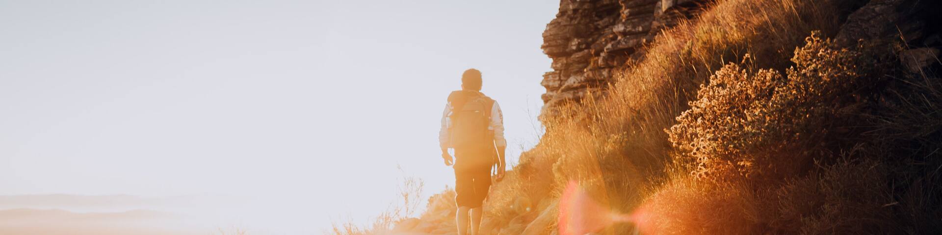 A person hiking on a rocky path with a city in the background.