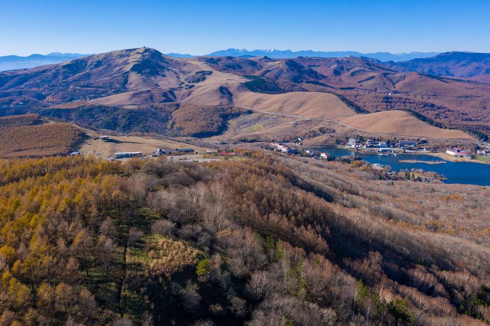 Un paysage montagneux avec un lac, une petite ville et des arbres aux couleurs automnales.