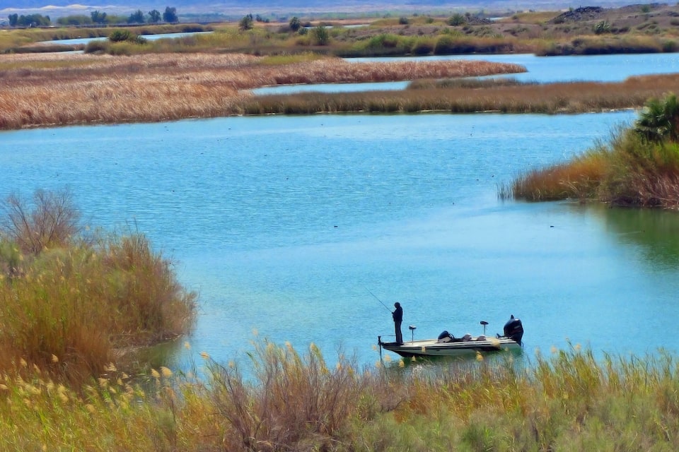 Un río tranquilo con un bote y una persona pescando.